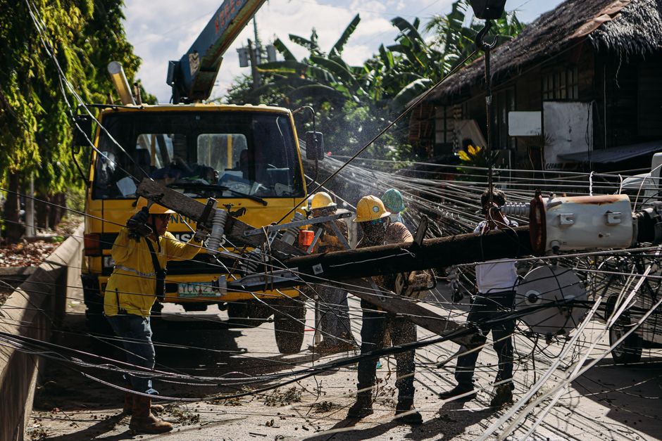 Utility workers repairing fallen power lines in a city street, highlighting teamwork and infrastructure maintenance.