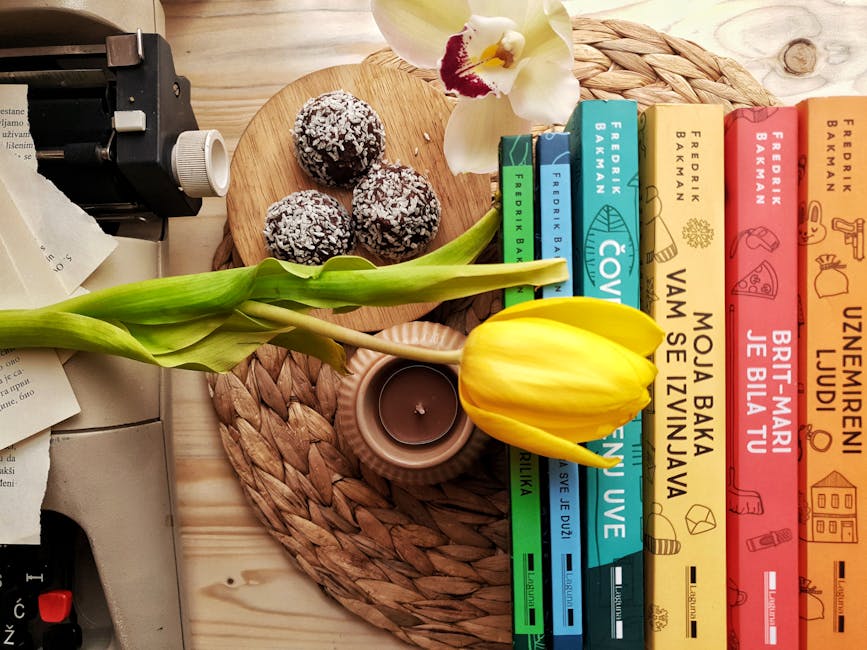 Top view stack of books on table near beautiful yellow tulip and orchid flowers arranged with chocolate truffles placed on wicker placemat