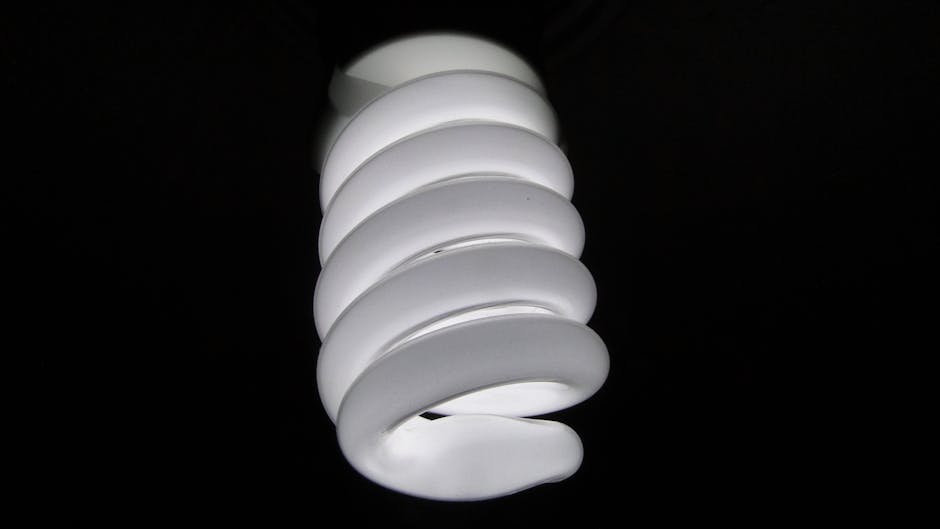 Detailed view of a spiral fluorescent light bulb on a black background.